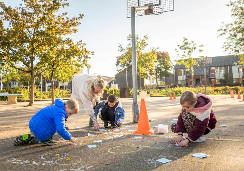 Kinderen tekenen met stoepkrijt op het schoolplein